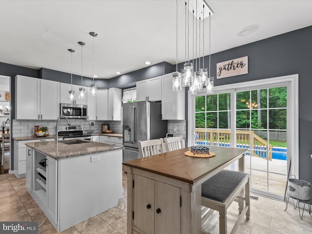 33759 Bay Ridge Ln, Lewes, DE 19958 - kitchen featuring stainless steel appliances, tasteful backsplash, an island with sink, stone counters, and white cabinets