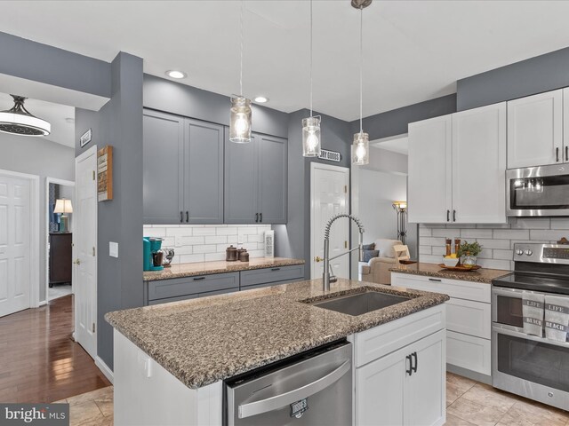33759 Bay Ridge Ln, Lewes, DE 19958 - kitchen with appliances with stainless steel finishes, a sink, stone counters, decorative backsplash, and a center island with sink