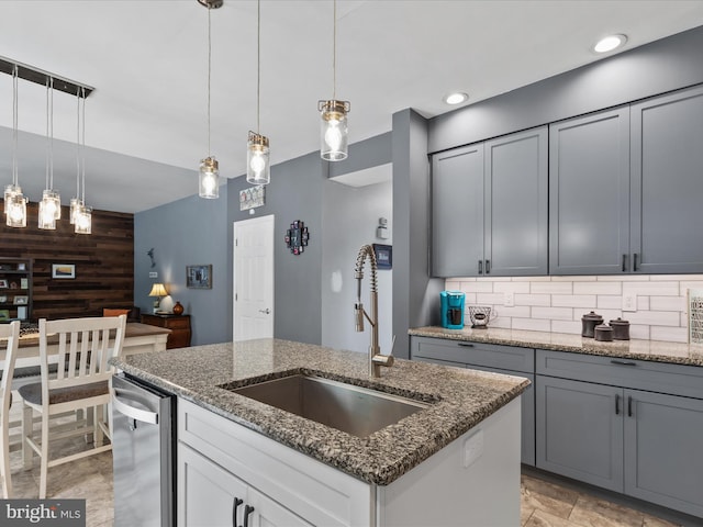33759 Bay Ridge Ln, Lewes, DE 19958 - kitchen featuring a sink, dark stone countertops, stainless steel dishwasher, a kitchen island with sink, and decorative light fixtures