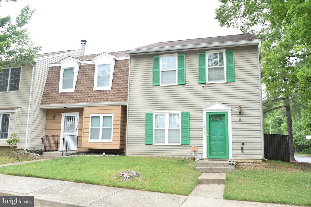 townhome / multi-family property with roof with shingles and a front lawn