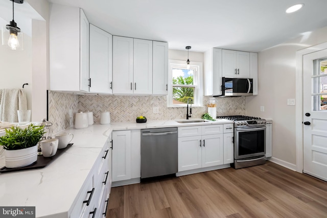 1233 Kendrick Rd, Rosedale, MD 21237 - kitchen featuring stainless steel appliances, a sink, backsplash, light wood-style floors, and white cabinetry