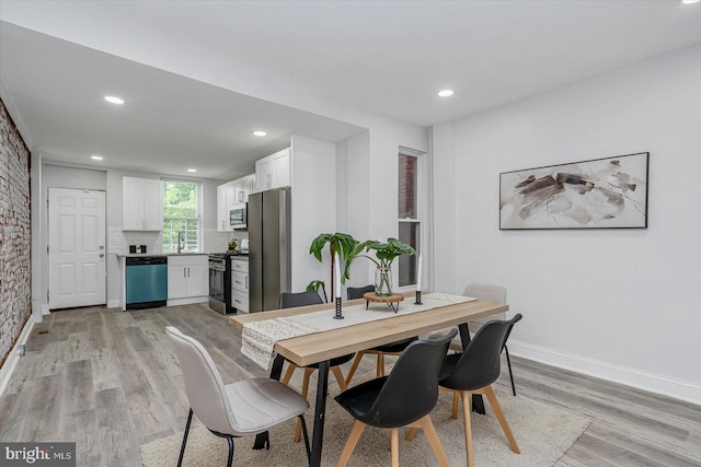 dining space with light wood-type flooring, baseboards, and recessed lighting