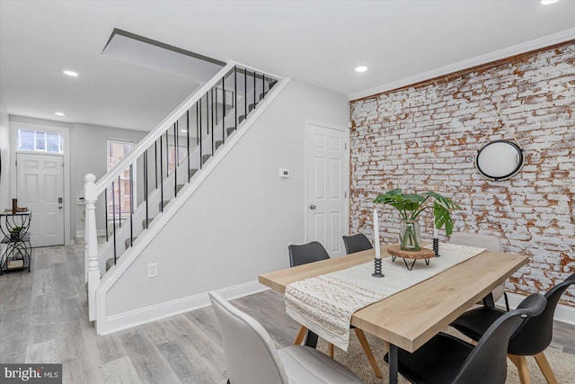 dining space featuring stairway, light wood finished floors, brick wall, recessed lighting, and baseboards