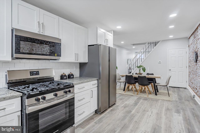 kitchen featuring appliances with stainless steel finishes, white cabinetry, decorative backsplash, light stone counters, and recessed lighting