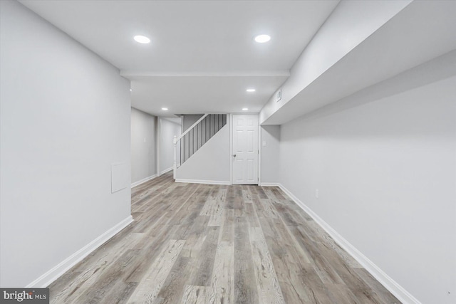 finished below grade area featuring wood finished floors, baseboards, recessed lighting, and stairway