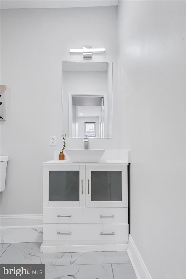 bathroom featuring marble look tiles, baseboards, and vanity