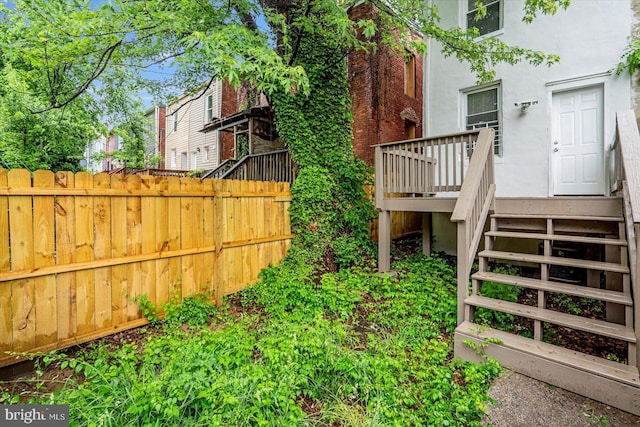 view of yard featuring fence, a wooden deck, and stairs