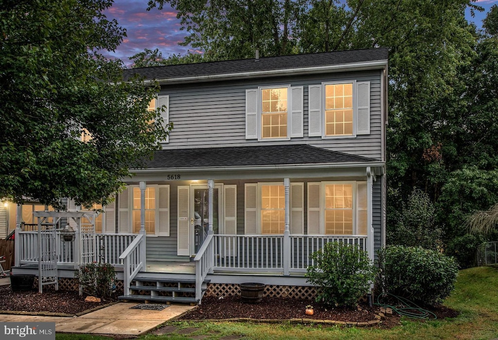 traditional home featuring a porch and roof with shingles