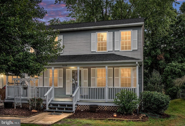 traditional home featuring a porch and roof with shingles