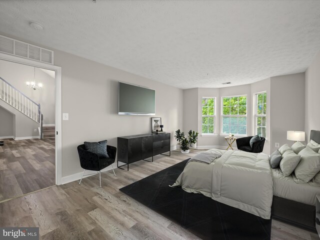 bedroom featuring wood finished floors, baseboards, a chandelier, and a textured ceiling