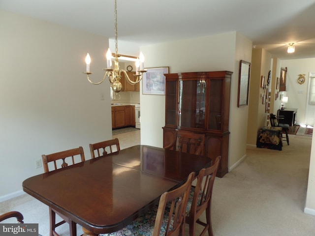 dining room with a chandelier, light colored carpet, and baseboards