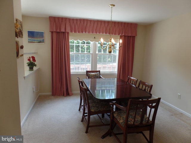 dining area with a chandelier, light carpet, and baseboards