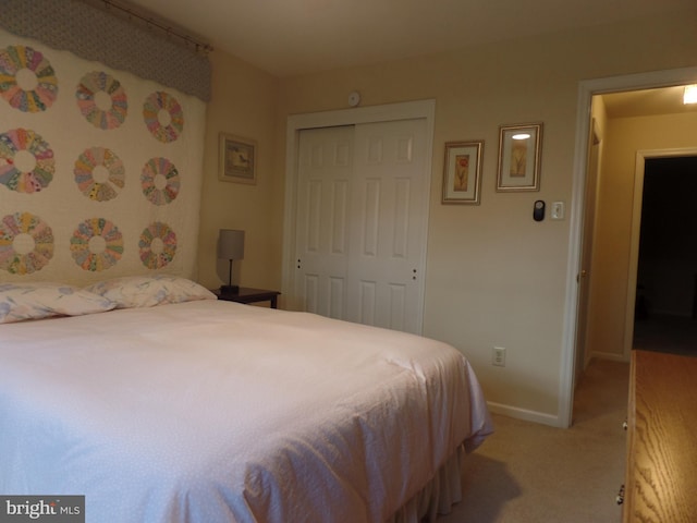 bedroom with a closet, light carpet, and baseboards
