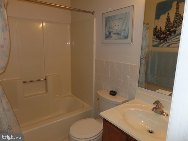 full bath with tile walls, toilet, vanity, a wainscoted wall, and shower / bathtub combination with curtain