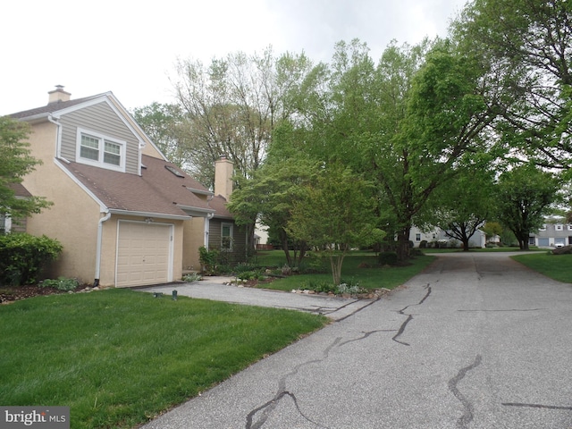 view of front of house featuring asphalt driveway, a front lawn, a chimney, and stucco siding