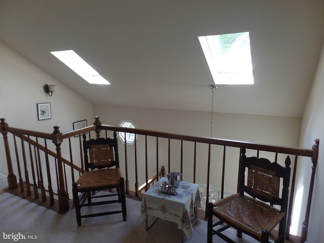 living area with a skylight, lofted ceiling, carpet, and an upstairs landing