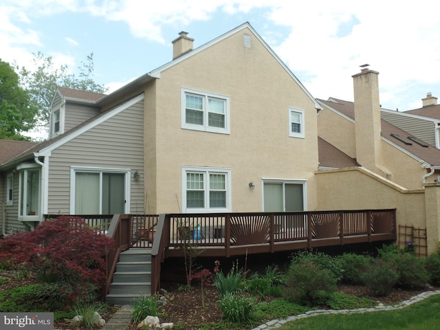 rear view of property with a chimney, a deck, and stucco siding
