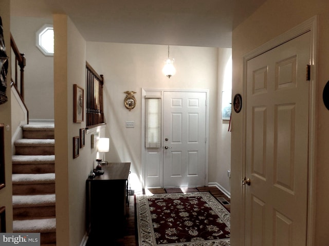 foyer entrance with stairway, baseboards, and dark wood-style floors