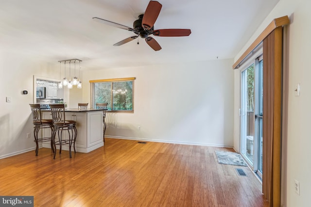 1211 Hesselius Ct, Annapolis, MD 21403 - kitchen with light wood-style floors, a breakfast bar, dark countertops, a peninsula, and ceiling fan