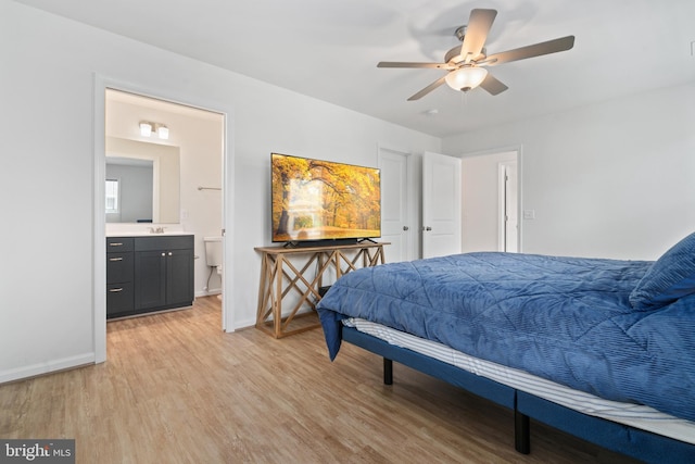 bedroom with baseboards, light wood finished floors, connected bathroom, and a sink