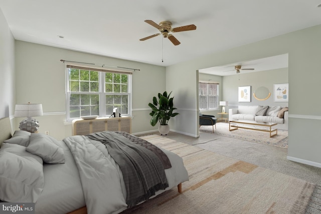 carpeted bedroom with multiple windows, baseboards, and a ceiling fan