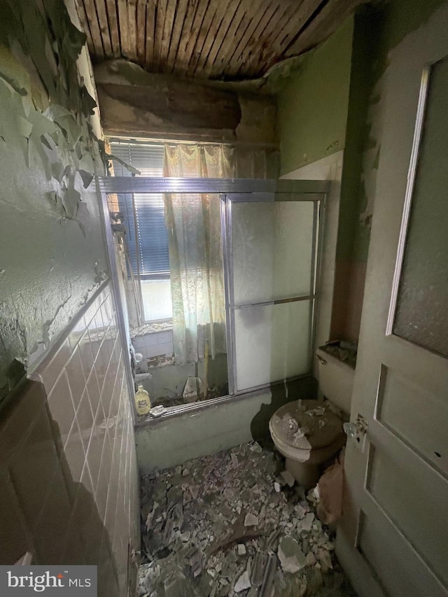 bathroom featuring toilet and bath / shower combo with glass door