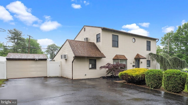 10 Queen Lily Rd, Levittown, PA 19057 - view of front facade featuring a garage, a wall unit AC, and roof with shingles
