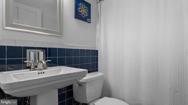 10 Queen Lily Rd, Levittown, PA 19057 - bathroom with tile walls, toilet, a wainscoted wall, and a sink