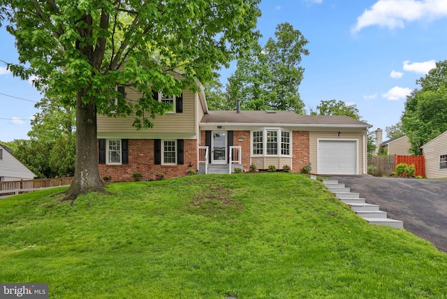split level home featuring asphalt driveway, an attached garage, and brick siding