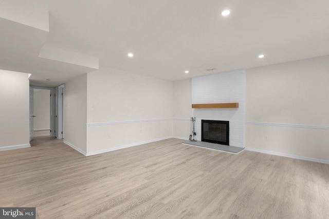 unfurnished living room featuring light wood-style flooring, a brick fireplace, recessed lighting, and baseboards