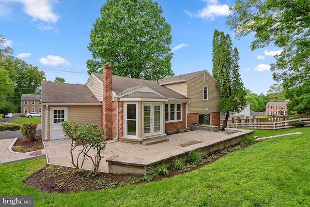 rear view of property with a patio, french doors, a chimney, and brick siding