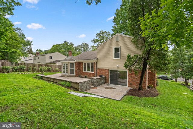 back of house with a patio area, brick siding, and a chimney