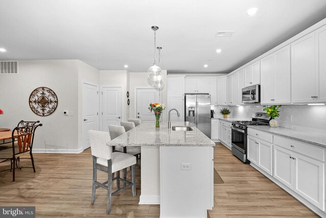3927 Fair Ridge Dr Unit 305, Fairfax, VA 22033 - kitchen with appliances with stainless steel finishes, a sink, a kitchen breakfast bar, white cabinetry, and light wood-style floors