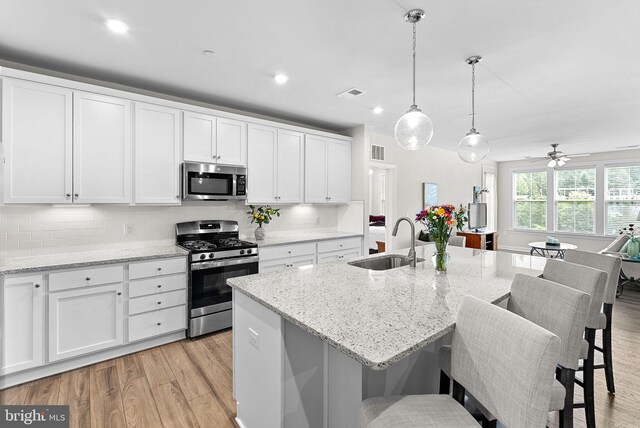 3927 Fair Ridge Dr Unit 305, Fairfax, VA 22033 - kitchen featuring stainless steel appliances, a sink, light wood-type flooring, white cabinetry, and decorative backsplash