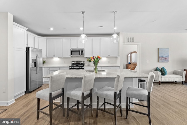 3927 Fair Ridge Dr Unit 305, Fairfax, VA 22033 - kitchen with appliances with stainless steel finishes, light wood-style flooring, white cabinets, a kitchen bar, and light stone counters
