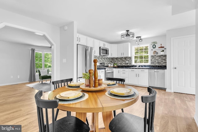 4152 Windy Hills Ln, King George, VA 22485 - dining area featuring light wood-style floors, arched walkways, and baseboards