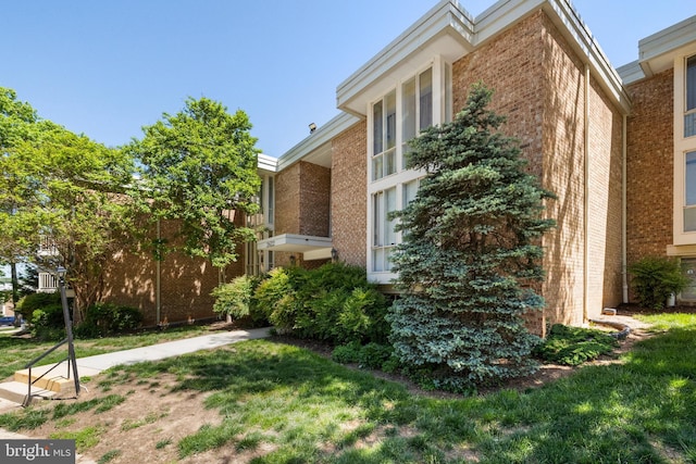 view of property exterior featuring brick siding and a lawn
