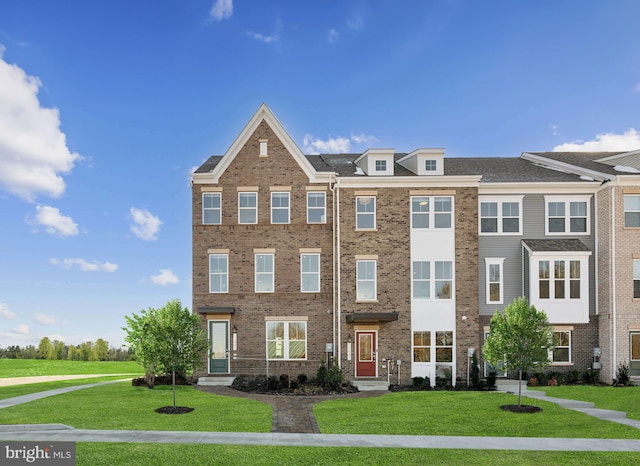 townhome / multi-family property with a front yard and brick siding