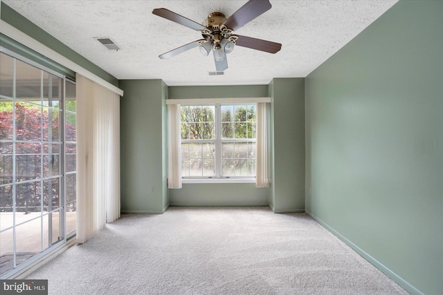 unfurnished room featuring ceiling fan, a textured ceiling, carpet, and visible vents