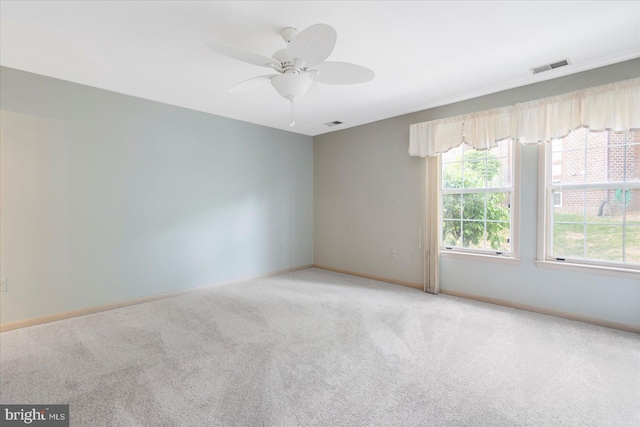 empty room featuring carpet flooring, baseboards, a ceiling fan, and visible vents
