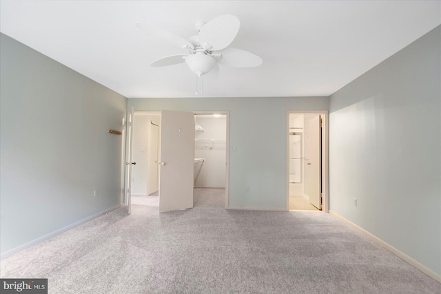 unfurnished bedroom with a closet, baseboards, a walk in closet, and carpet floors