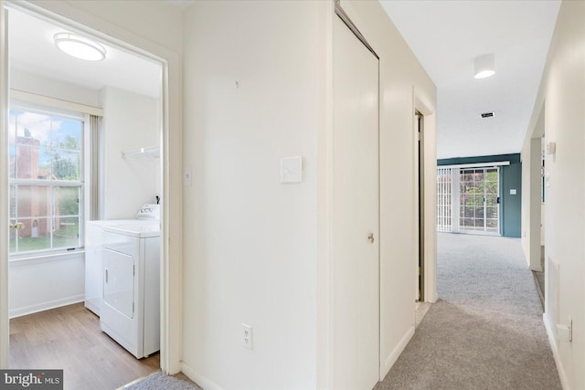 hallway with washer and clothes dryer and baseboards