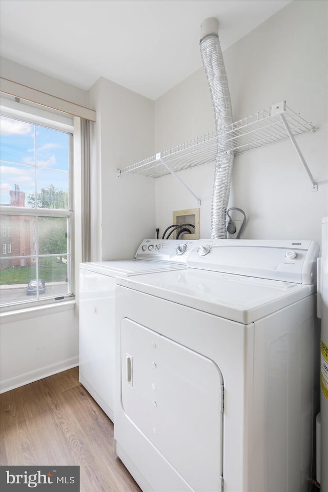 clothes washing area with washer and dryer, laundry area, light wood finished floors, and baseboards