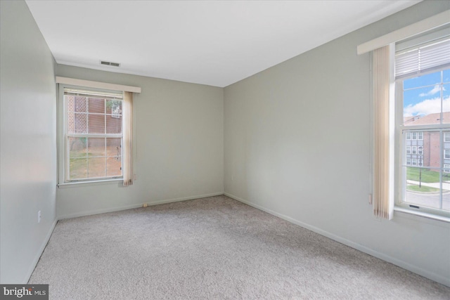 empty room featuring carpet flooring, visible vents, and baseboards