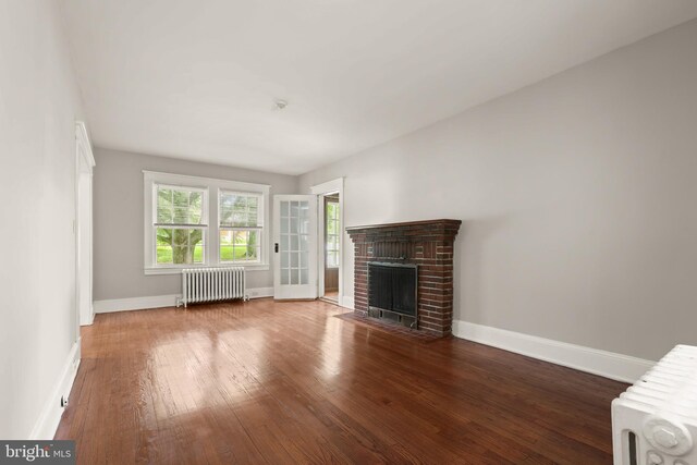 331 E Maple Rd, Linthicum Heights, MD 21090 - unfurnished living room with radiator heating unit, hardwood / wood-style flooring, baseboards, and a brick fireplace