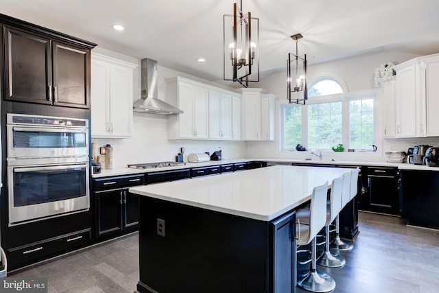 4902 Bridle Ridge Rd, Upper Marlboro, MD 20772 - kitchen featuring wood finished floors, wall chimney exhaust hood, stainless steel appliances, light countertops, and a kitchen island