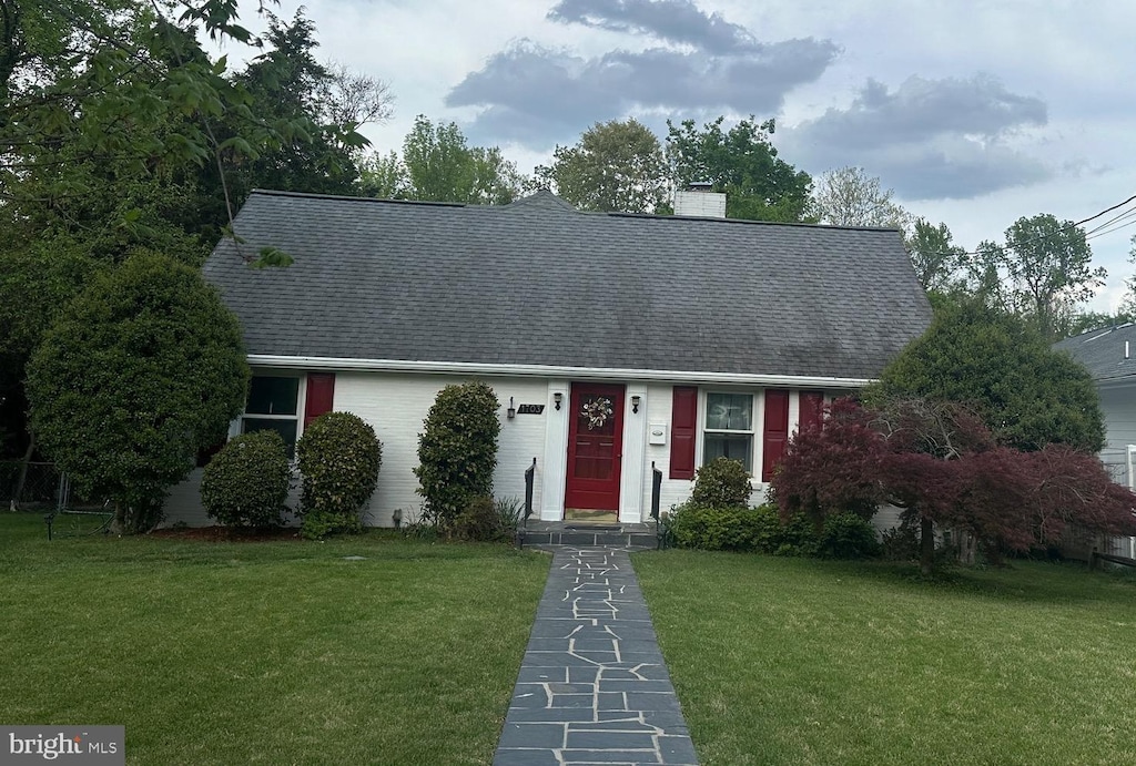 view of front of home with a chimney, a front yard, and a shingled roof