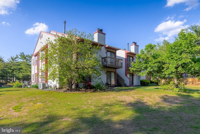 rear view of property featuring a chimney, a yard, cooling unit, and a wooden deck