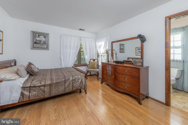 bedroom with light wood-type flooring and ensuite bathroom