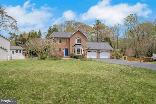 colonial house with an attached garage, fence, a front yard, brick siding, and driveway